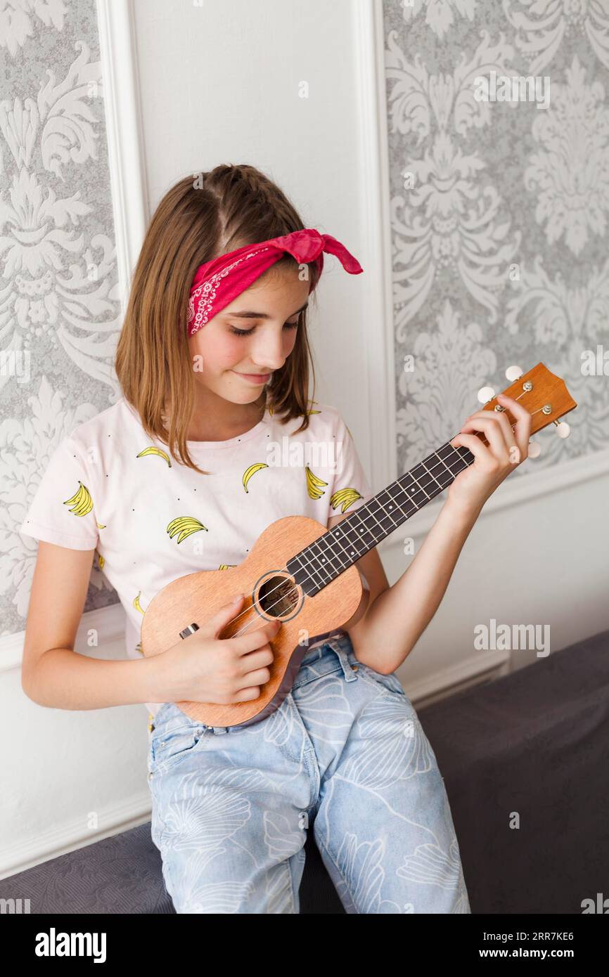 Smiling little girl playing ukulele home Stock Photo Alamy