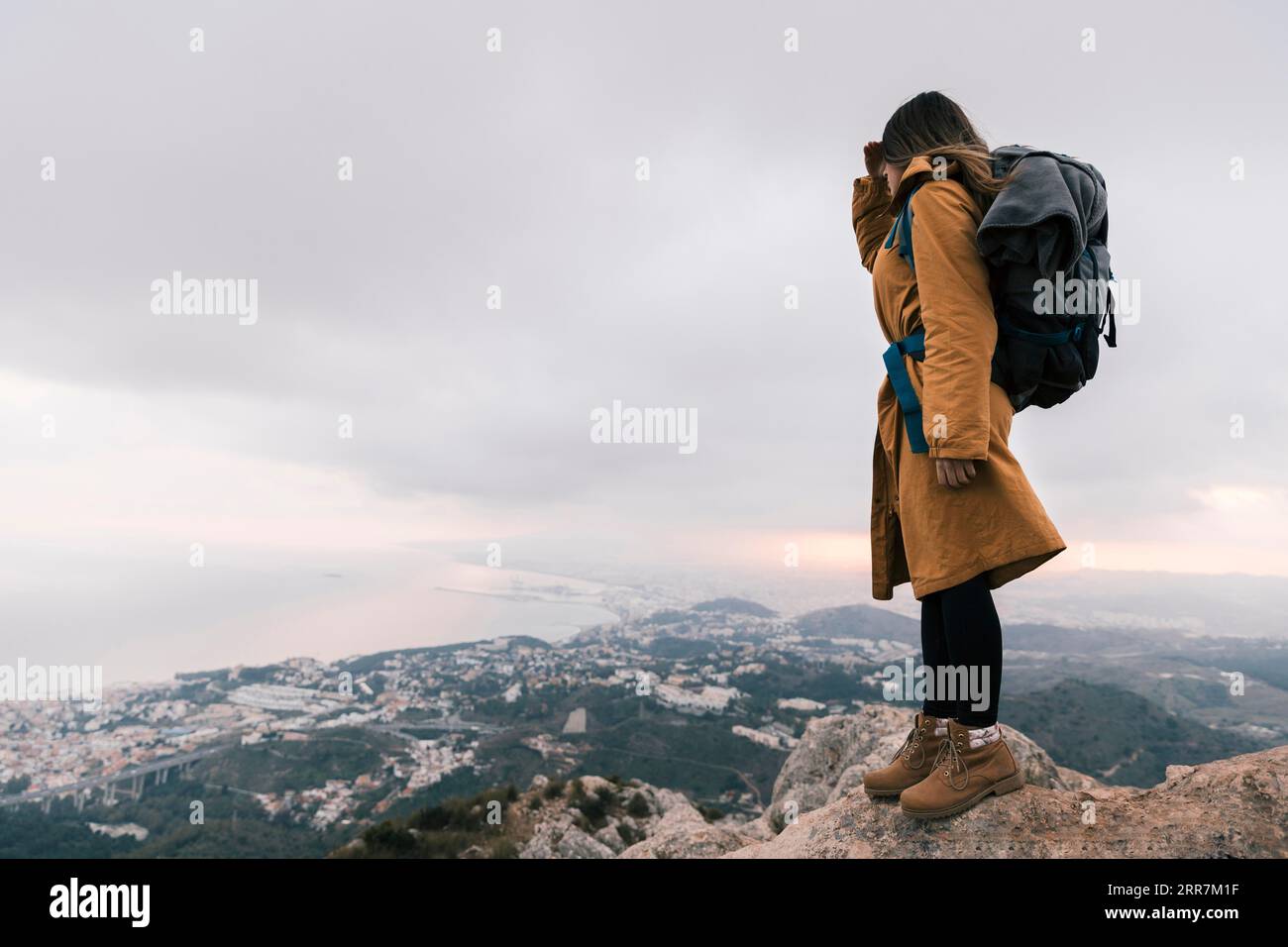 Young woman with her backpack standing top mountain looking idyllic view Stock Photo