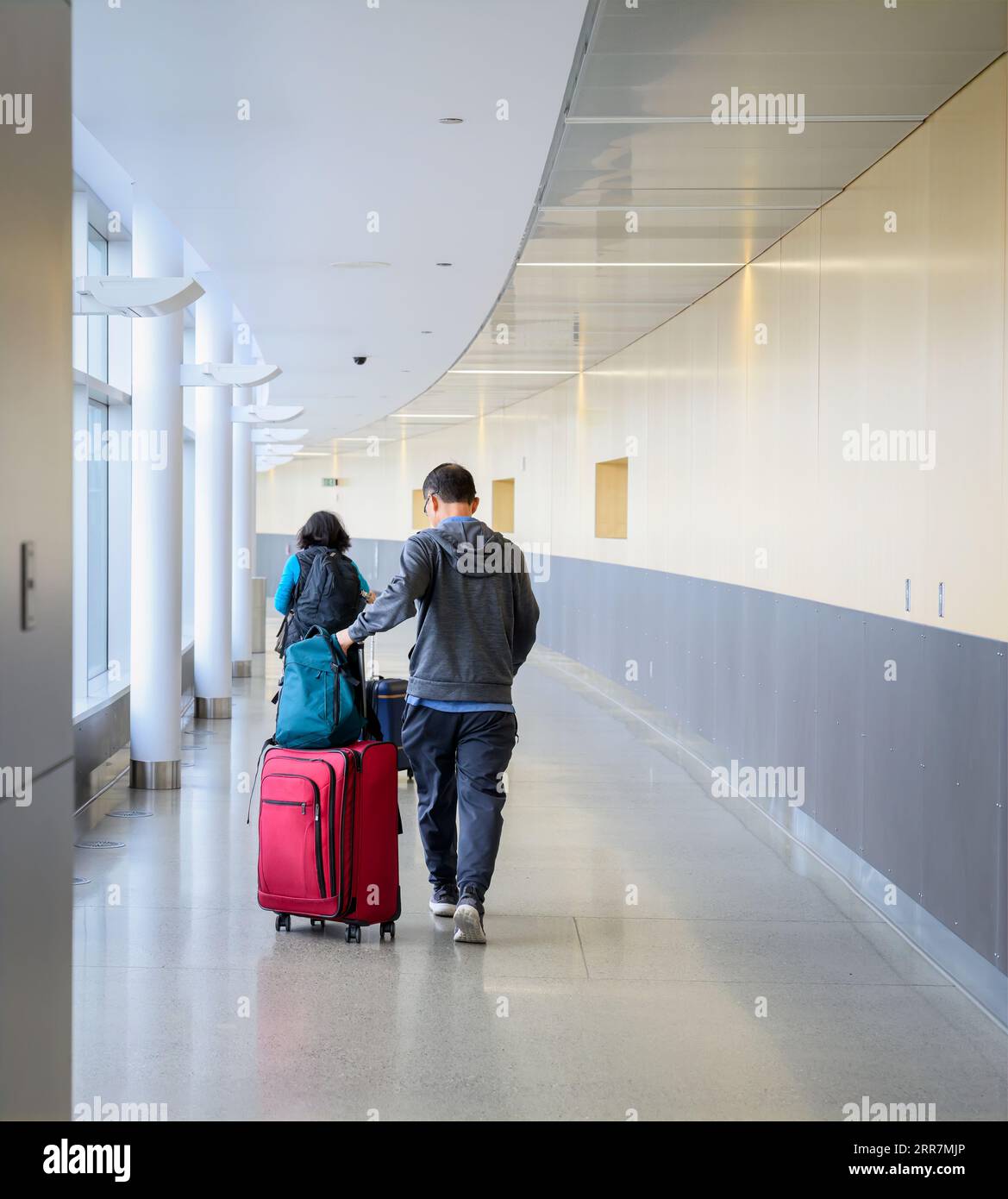Couple pushing luggage bags at the airport, ready to board the flight. Vertical format. Stock Photo