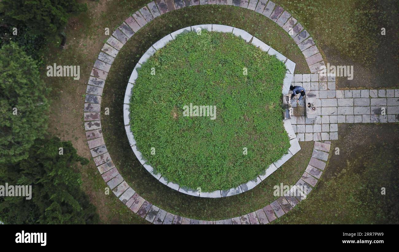 210402 -- DANGTU, April 2, 2021 -- Aerial photo taken on March 31, 2021 shows Gu Changxin cleans Li Bai s tomb at Li Bai cultural park, in Dangtu County of Maanshan City, east China s Anhui Province. The tomb of Li Bai, a famous poet of Tang Dynasty 618-907, is located at the foot of Qingshan Mountain in Dangtu County of Maanshan City. After Li Bai died in Dangtu, his good friend Gu Lanxin offered his land as Li Bai s burial place. Since then, the Gu s family has become the guardian of Li Bai s tomb, which continues to this day. In 1985, 18-year-old Gu Changxin became the 49th generation tomb Stock Photo