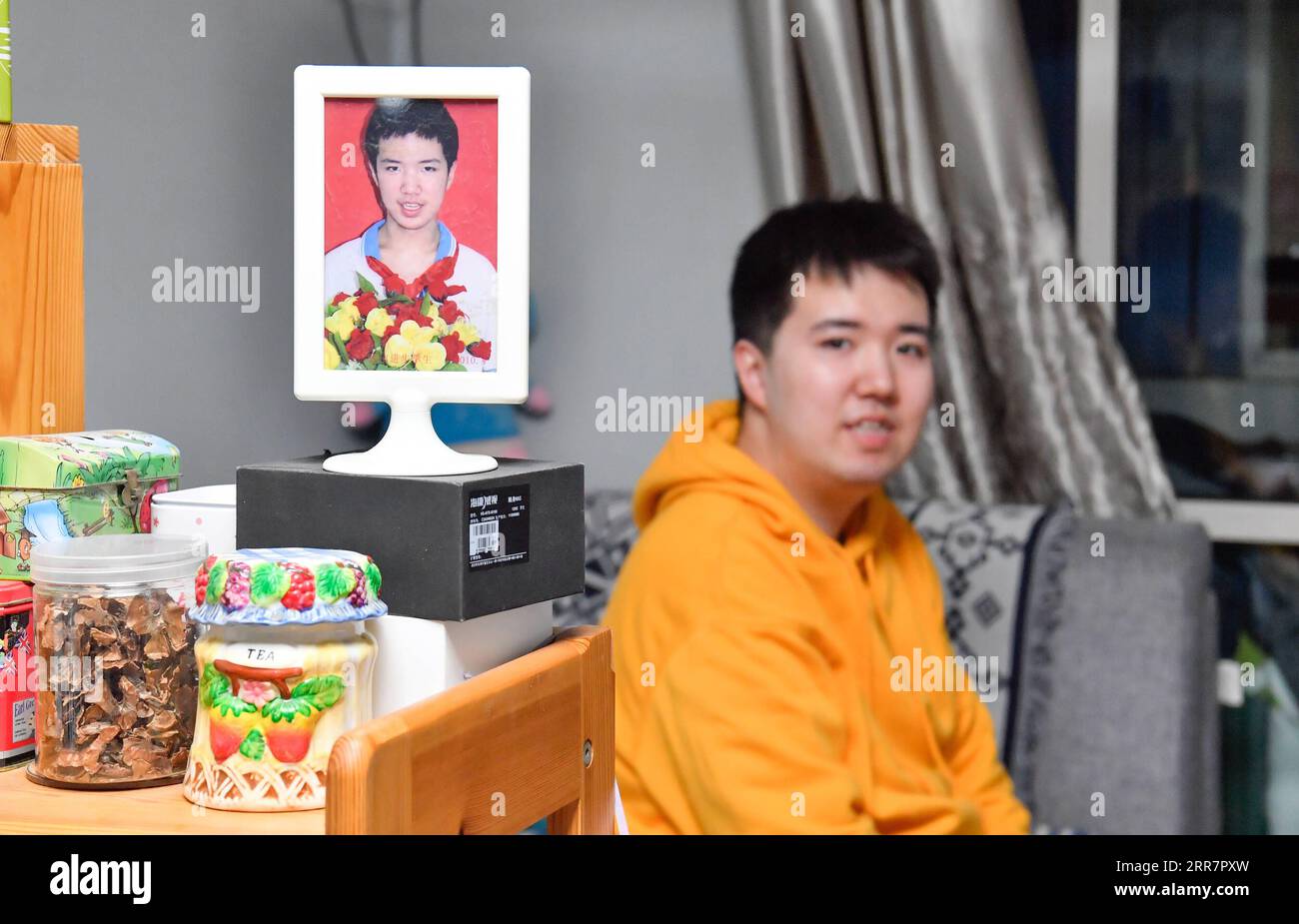 210402 -- TIANJIN, April 2, 2021 -- Photo shows Zhang Hao posing with a portrait of him when he graduated from a school for people with autism in Hebei District, north China s Tianjin, March 29, 2021. In 1998, Zhang Hao was diagnosed with autism at the age of two. Ever since the diagnosis, Zhang s mother Wu Guixiang has spent all her time looking after her son. In order to help Zhang Hao and eight others with autism improve their social engagement after they had become grown-ups, Wu set up an autism training center in 2016, providing them with courses on life, social and vocational skills. Wit Stock Photo