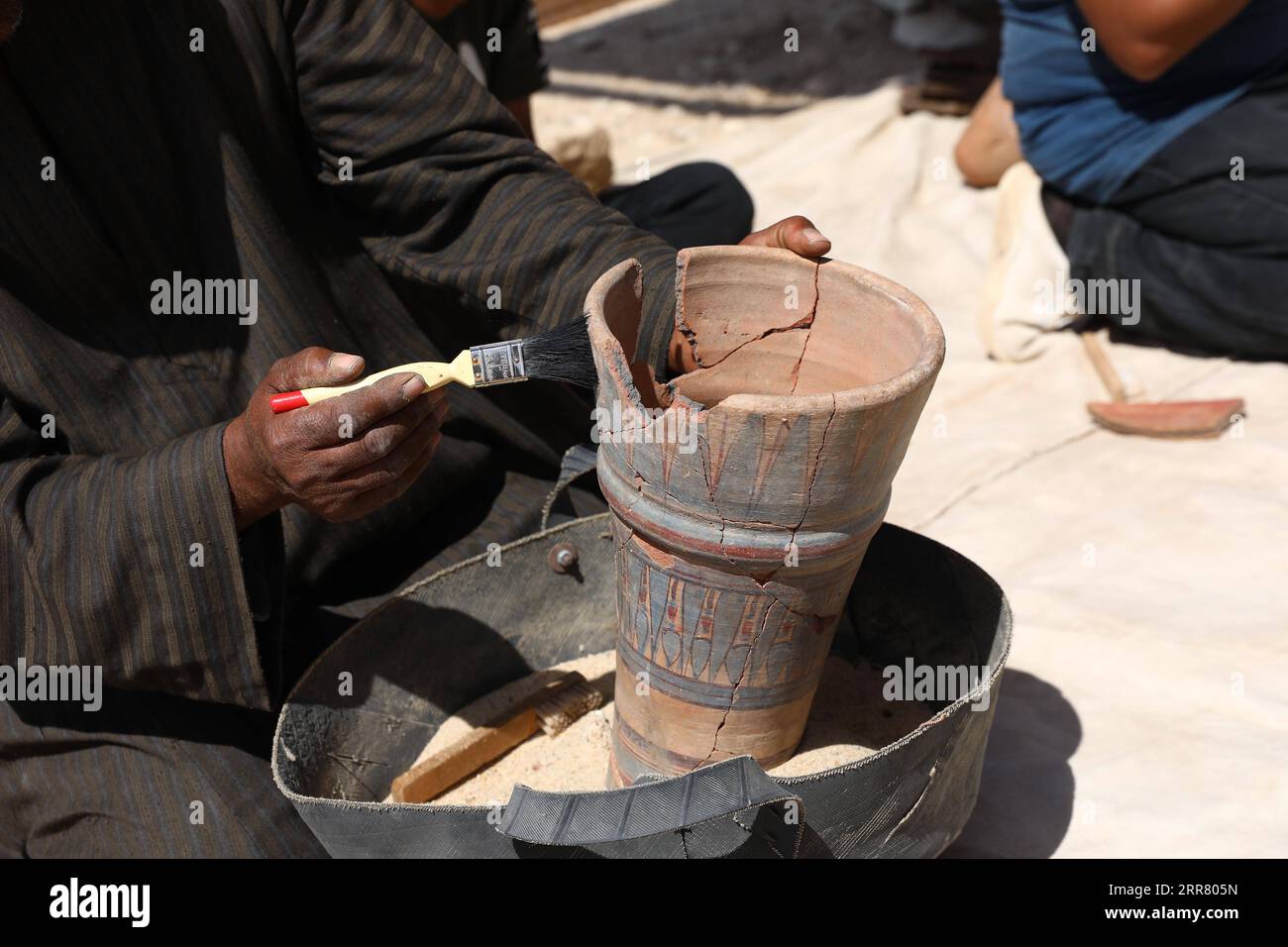 210410 -- LUXOR, April 10, 2021 -- An excavation worker cleans a pottery vessel unearthed from the archeological site of the Lost Gold City in Luxor, Egypt, April 10, 2021. An Egyptian archeological mission announced on Thursday the discovery of a 3,000-year-old Lost Gold City LGC in Egypt s monument-rich city of Luxor. An Egyptian mission, headed by renowned Egyptian archeologist Zahi Hawass, in collaboration with Egypt s Supreme Council of Antiquities, found the city that was lost under the sand. The city, known as The Rise of Aten, dates back to the reign of Amenhotep III, and continued to Stock Photo