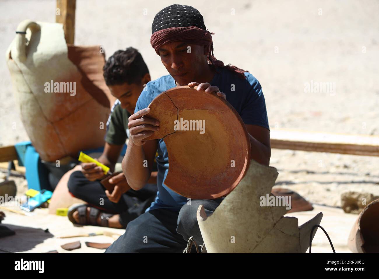 210410 -- LUXOR, April 10, 2021 -- An excavation worker fixes a pottery plate unearthed from the Lost Gold City in Luxor, Egypt, April 10, 2021. An Egyptian archeological mission announced on Thursday the discovery of a 3,000-year-old Lost Gold City LGC in Egypt s monument-rich city of Luxor. An Egyptian mission, headed by renowned Egyptian archeologist Zahi Hawass, in collaboration with Egypt s Supreme Council of Antiquities, found the city that was lost under the sand. The city, known as The Rise of Aten, dates back to the reign of Amenhotep III, and continued to be used by king Tutankhamun. Stock Photo