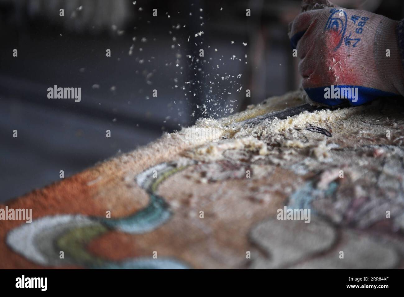 210418 -- TIANSHUI, April 18, 2021 -- A worker flattens a silk carpet in Xintian Silk Carpet Company in Tianshui City, northwest China s Gansu Province, April 12, 2021. The city of Tianshui in northwest China s Gansu Province has a long tradition of making silk carpets. The technique, which involves more than 20 procedures, was listed as a national intangible cultural heritage in 2014 due to its artistic value and complexity. Huang Jingrong, 49, embarked on her journey of making silk tapestries at the age of 18 in Xintian Silk Carpet Company. Since the first day, she never shied away from the Stock Photo