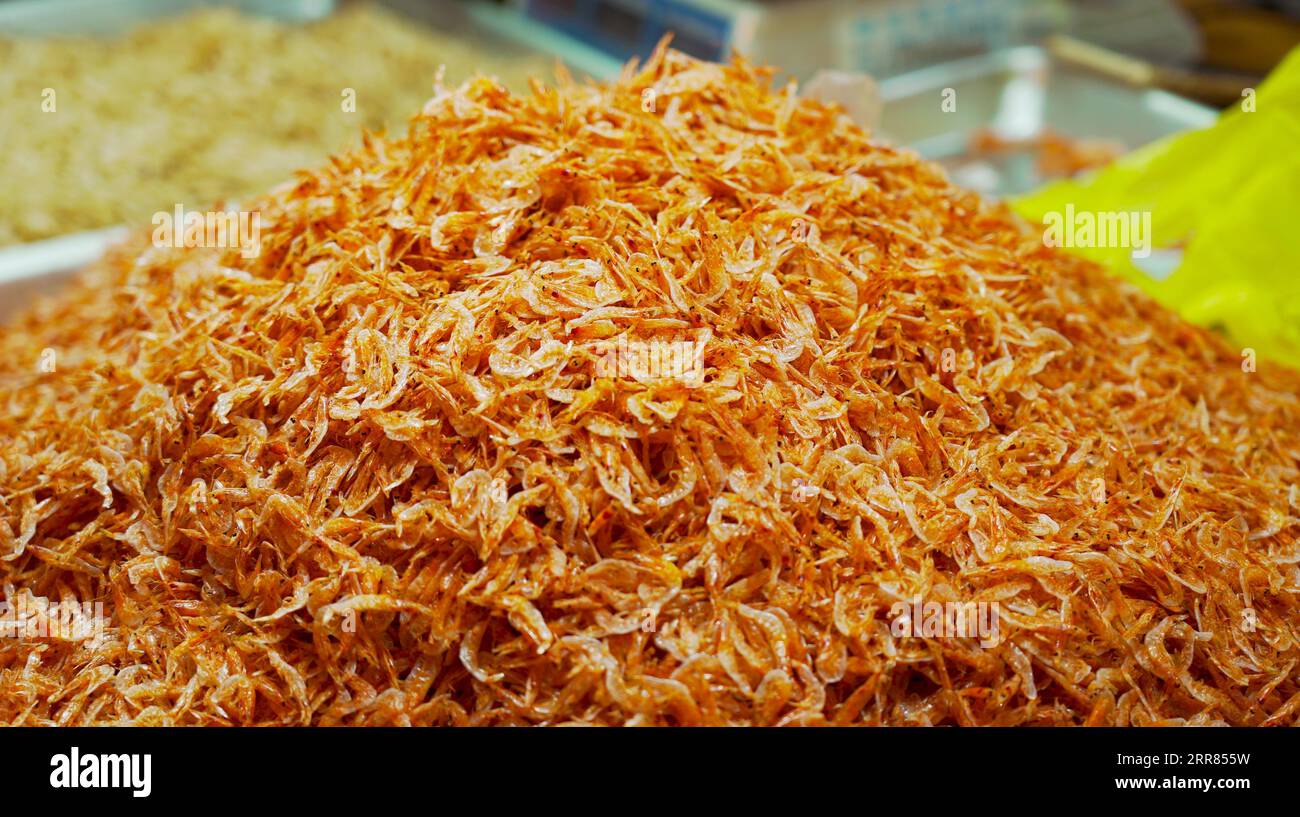 A pile of dried shrimp in abundance. Inside the shop, the shelves are filled to the brim with mounds of shrimp, creating a sea of seafood bounty Stock Photo