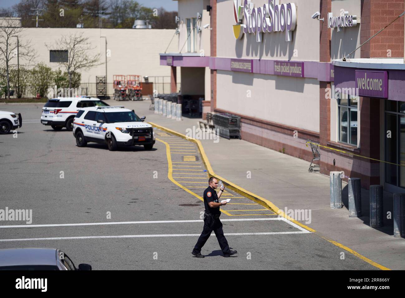 210420 -- NEW YORK, April 20, 2021 -- A police officer walks toward a Stop & Shop grocery store where a shooting took place in West Hempstead, New York, the United States, on April 20, 2021. A suspect in a shooting at the suburban New York grocery store on Tuesday was arrested after remaining at large for hours, local police said. The shooting, leaving one dead and two others injured, occurred late morning Tuesday at an office of the Stop & Shop grocery store in West Hempstead, according to police.  U.S.-NEW YORK-WEST HEMPSTEAD-SHOOTING WangxYing PUBLICATIONxNOTxINxCHN Stock Photo