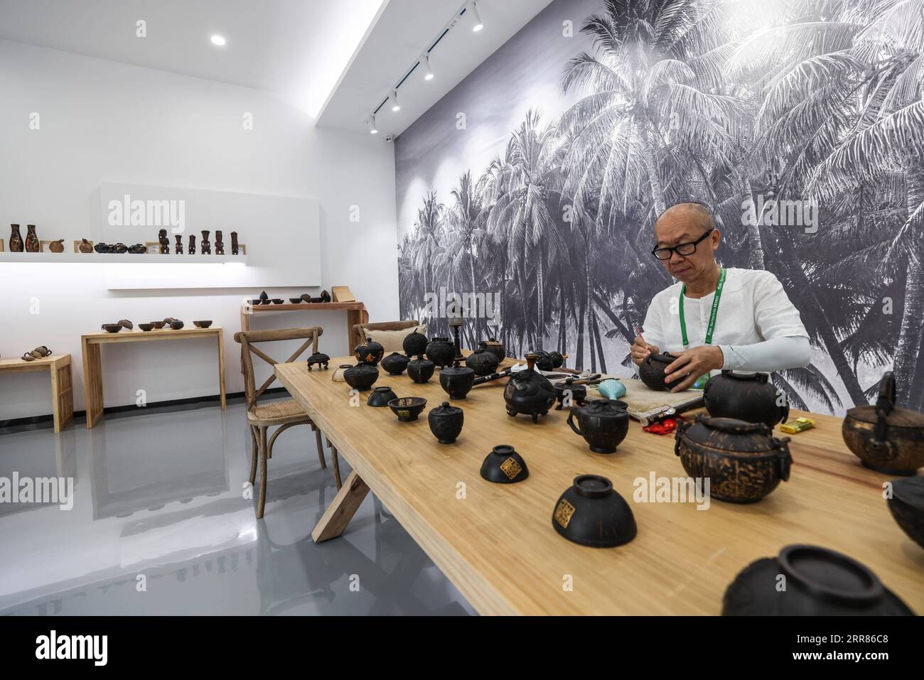 210421 -- BOAO, April 21, 2021 -- A craftsman makes sculptures with coconut shells at an exhibition hall of the Boao Forum for Asia BFA theme park in Boao, south China s Hainan Province, on April 20, 2021. The park, opened to the public on Monday, is located near the BFA permanent venue, comprising nine yards displaying Hainan specialties.  CHINA-HAINAN-BOAO-BFA THEME PARK CN ZhangxLiyun PUBLICATIONxNOTxINxCHN Stock Photo