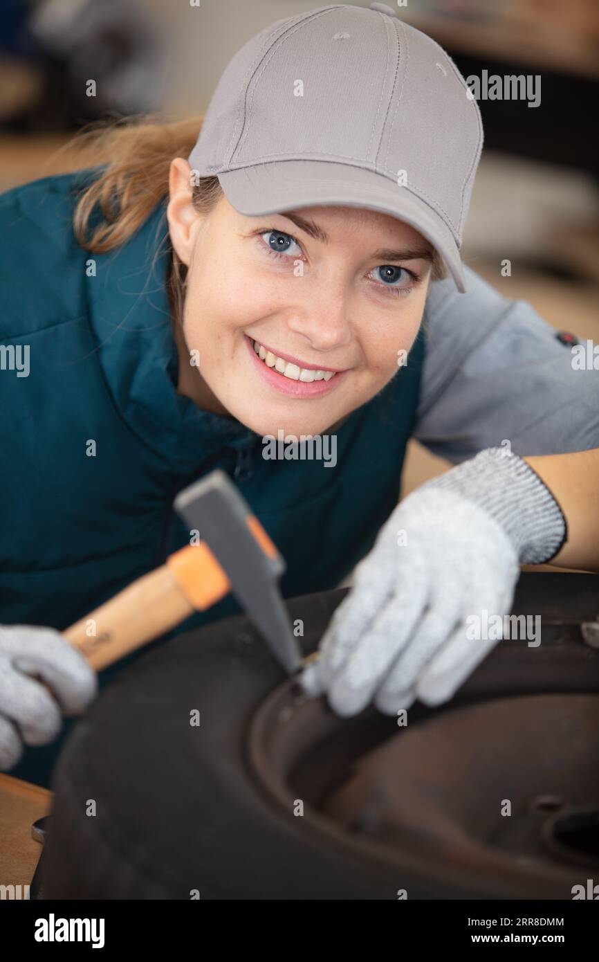 female mechanic using a hammer while working on a tyre Stock Photo