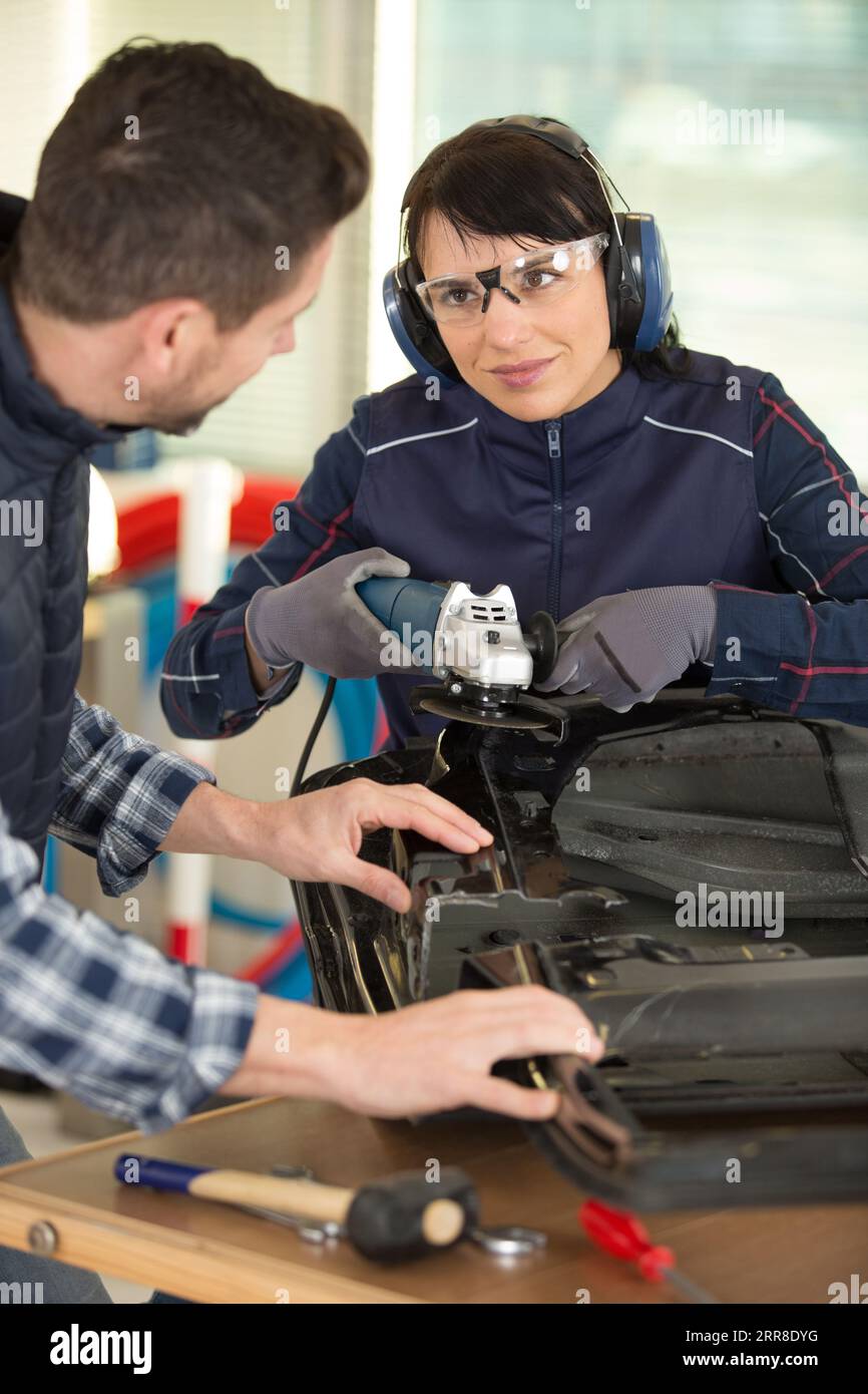 female trainee using angle grinder in workshop Stock Photo
