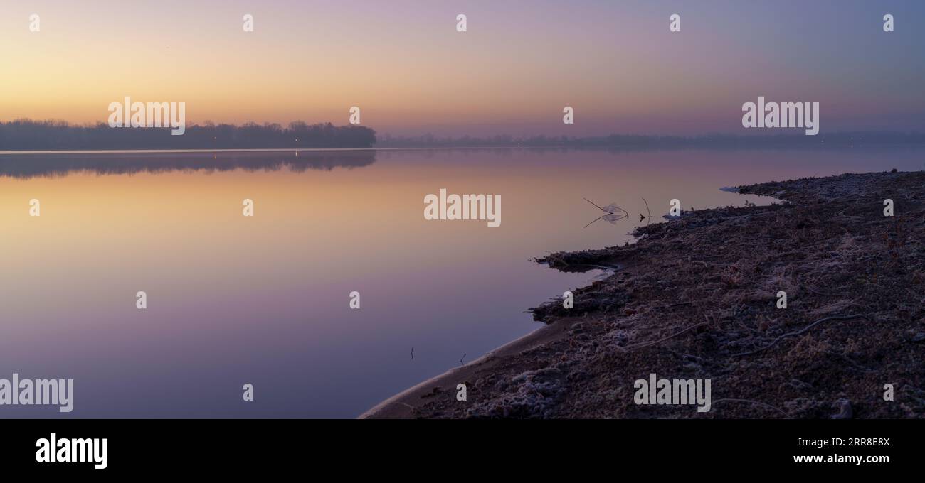 A tranquil lake scene featuring a small wooden boat floating peacefully ...
