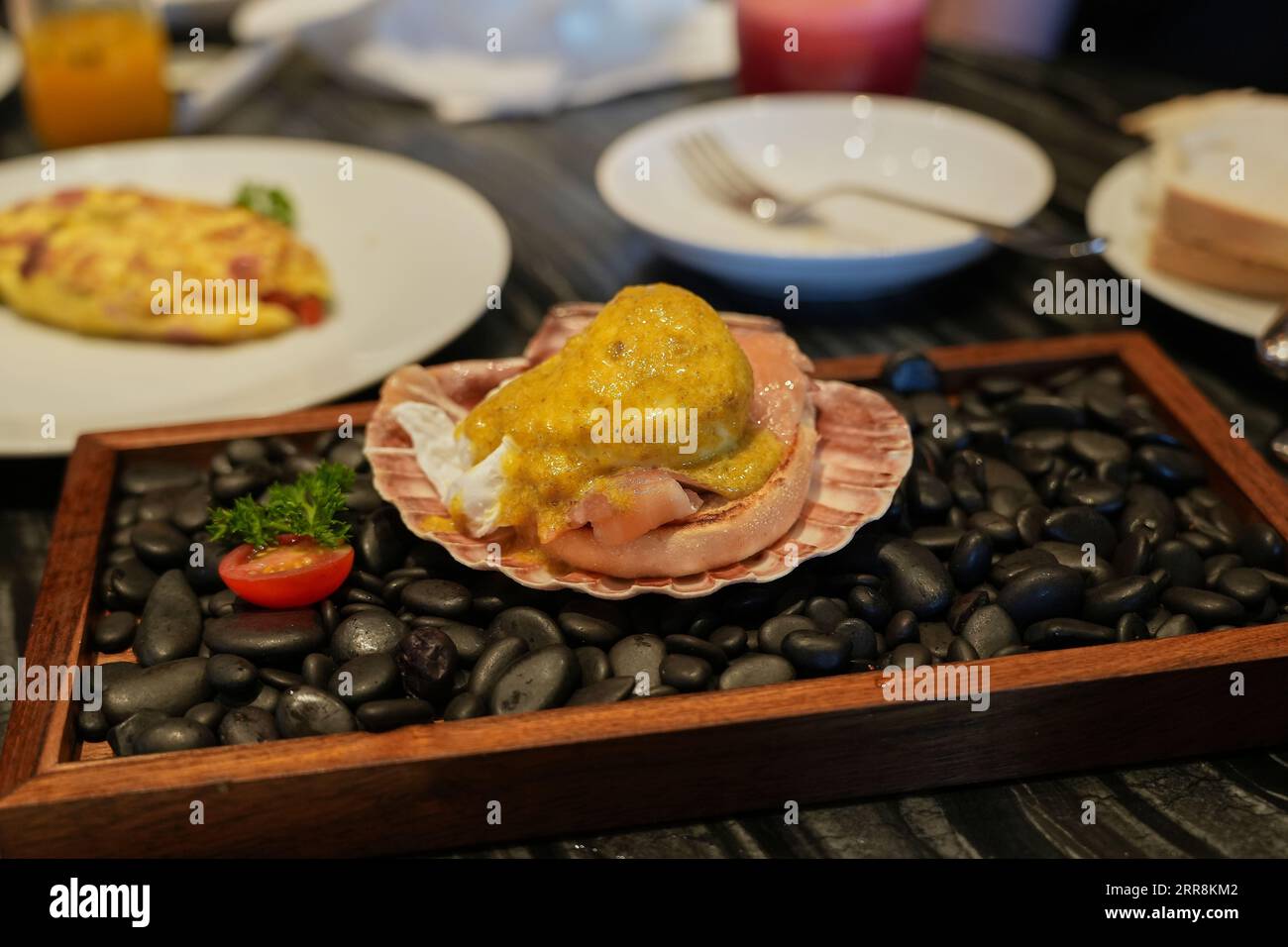 Eggs Benedict with Decorative Clams and Black Pebbles Stock Photo