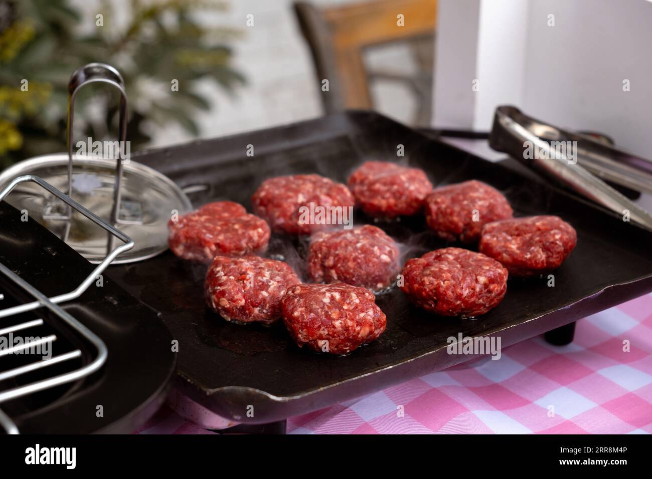 The ground beef cooking on the spit to prepare hamburgers Stock Photo
