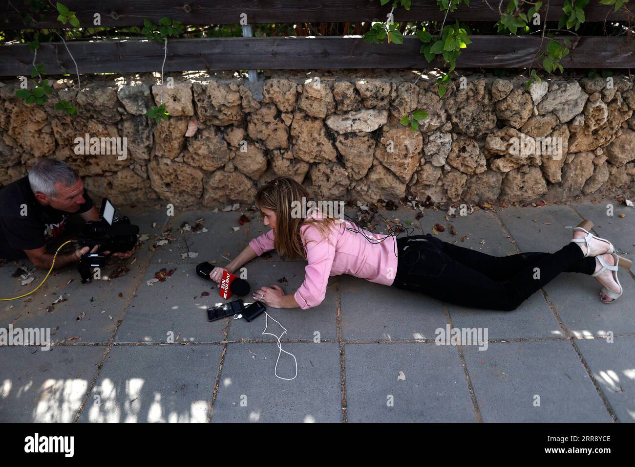 210520 -- ASHKELON ISRAEL, May 20, 2021 -- People take cover as a siren warning of incoming rockets fired from the Gaza Strip sounds in Ashkelon, southern Israel, on May 20, 2021. Both Israel and Hamas, which rules the Gaza Strip, have accepted an Egyptian-brokered deal to cease fighting at 2 a.m. Friday local time 2300 GMT Thursday to end the 11-day bloodshed. The heaviest fighting between Israel and Gaza militants since 2014 has so far killed 232 Palestinians, including 65 children and 39 women, and 12 Israelis.  via Xinhua ISRAEL-ASHKELON-ROCKET-ATTACK IlanxAssayag/JINI PUBLICATIONxNOTxINxC Stock Photo