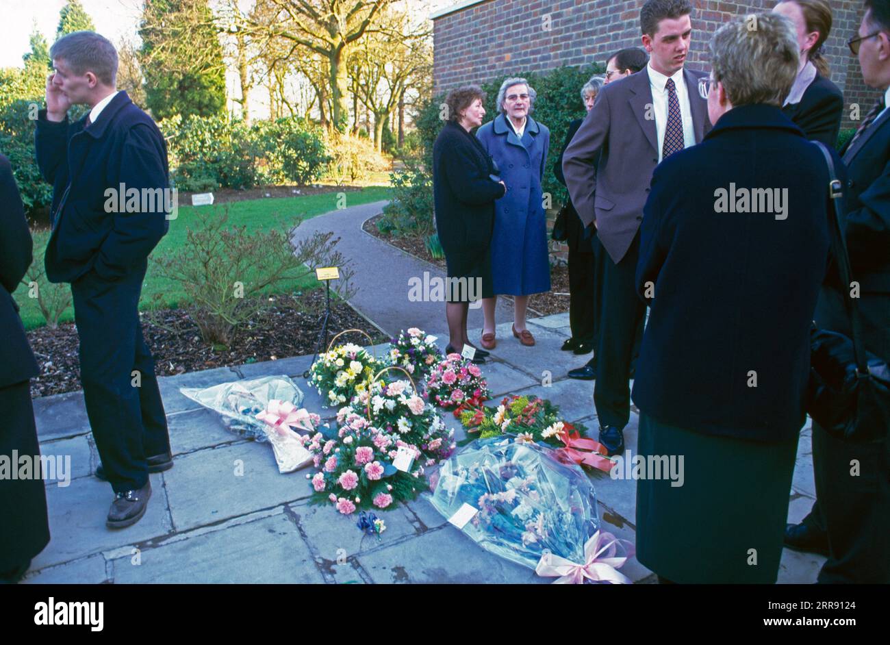 Mourners Outside After Cremation Flowers On Ground in Remembrance England Stock Photo