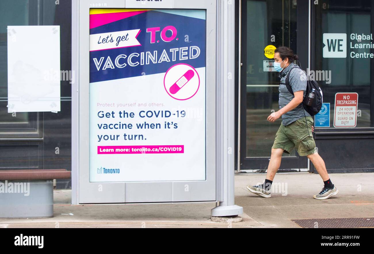 210523 -- TORONTO, May 23, 2021 -- A man wearing a face mask walks past a poster displaying information about the COVID-19 vaccination in Toronto, Canada, on May 22, 2021. About 50.08 percent of Canada s population were administered with the first dose of COVID-19 vaccine and 4.3 percent with second dose as of Saturday afternoon, according to CTV. Photo by /Xinhua CANADA-TORONTO-COVID-19-VACCINATION ZouxZheng PUBLICATIONxNOTxINxCHN Stock Photo