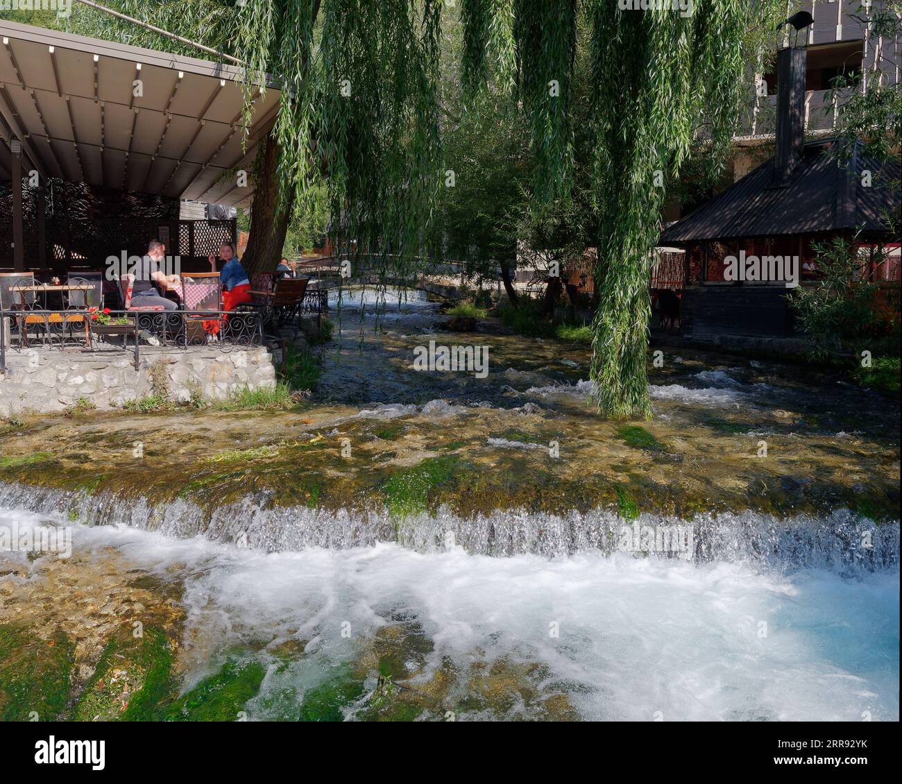 People sit at a cafe/restaurant beside a stream in the town of Travnik, Bosnia and Herzegovina, September 06, 2023 Stock Photo