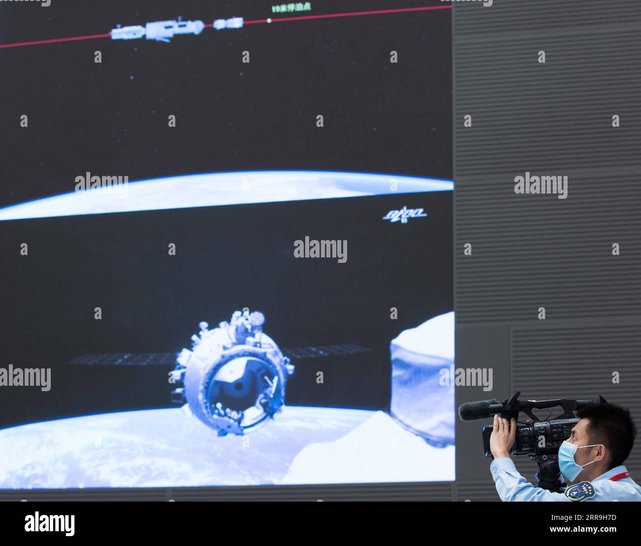 210617 -- BEIJING, June 17, 2021 -- A staff member takes videos of the screen image showing China s Shenzhou-12 manned spaceship docking with the space station core module Tianhe at Beijing Aerospace Control Center in Beijing, capital of China, June 17, 2021. China s Shenzhou-12 manned spaceship has successfully docked with the space station core module Tianhe on Thursday, according to the China Manned Space Agency CMSA. The spaceship, launched on Thursday morning, completed orbital status setting after entering the orbit and conducted a fast autonomous rendezvous and docking with the front do Stock Photo