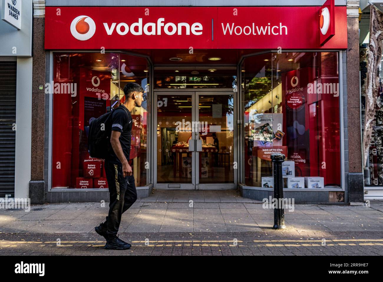 London, UK. 21st Aug, 2023. People walk past Vodafone store logo
