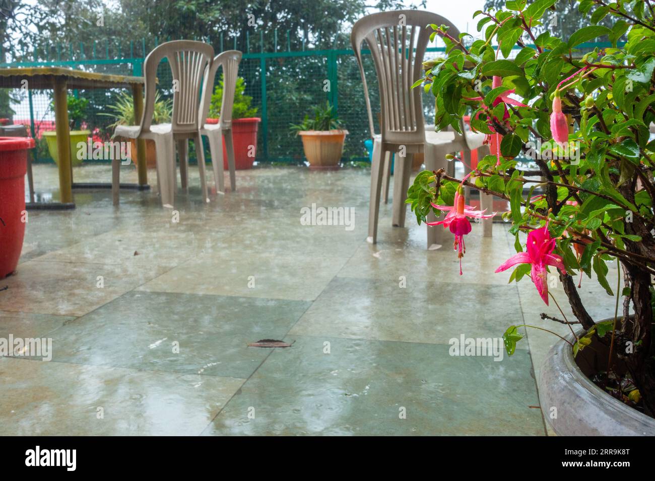 An image of an outdoor garden balcony with empty chairs and a table during a rainy monsoon season in Himachal Pradesh, India Stock Photo