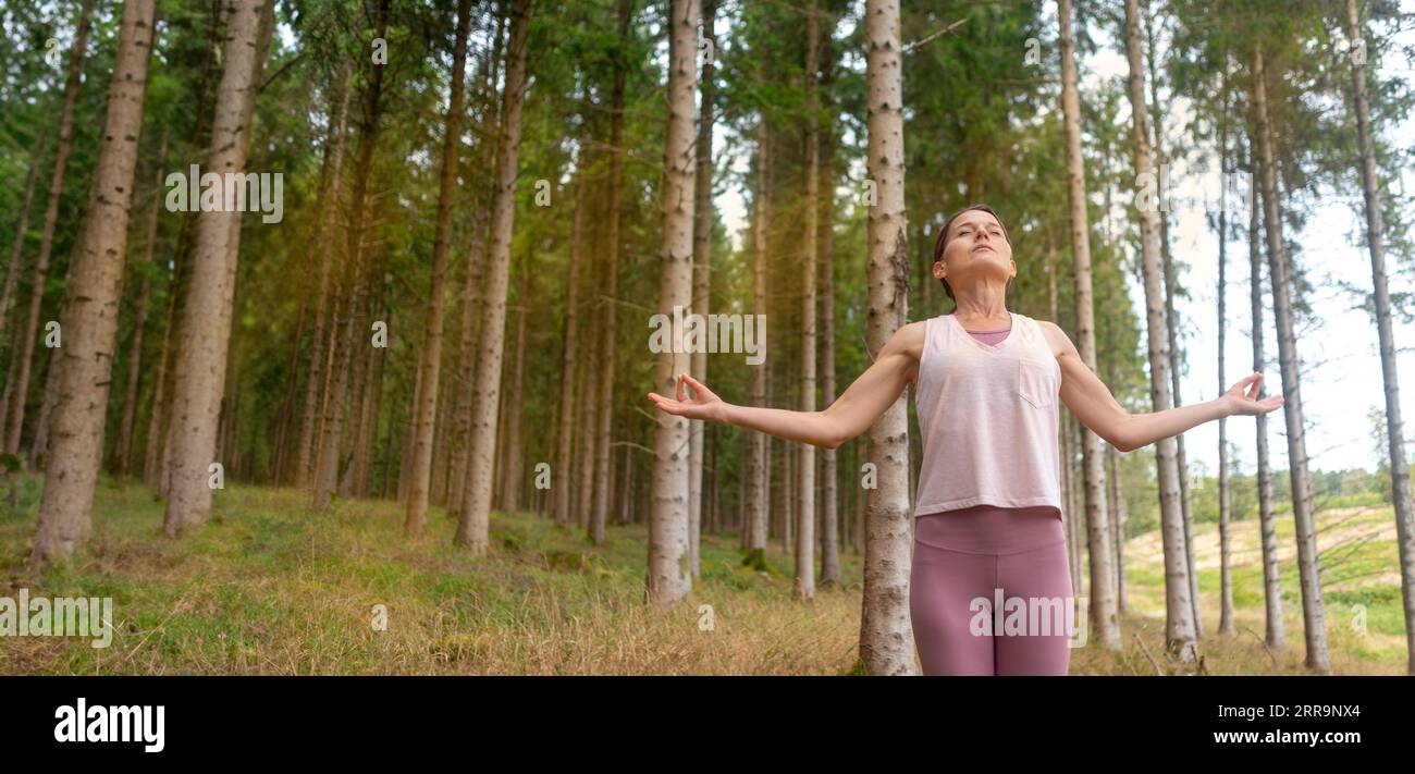 sporty woman breathing deeply fresh air in a forest meditating outdoors Stock Photo