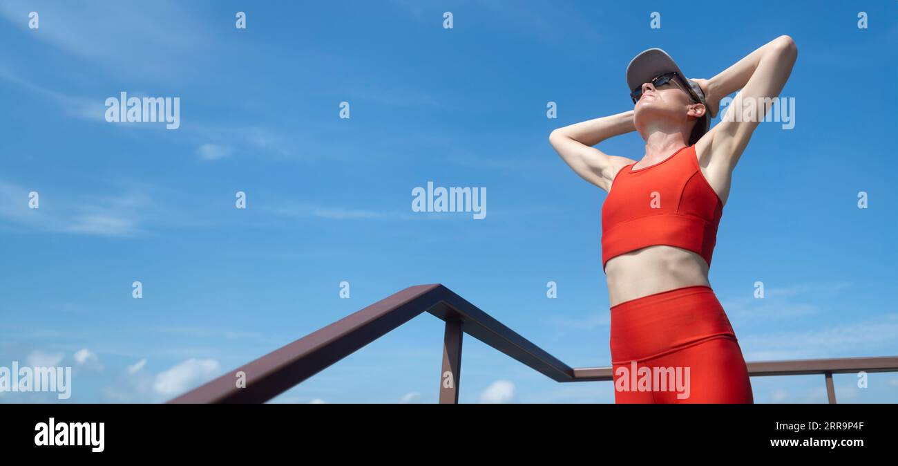 Sporty woman with hands on her head catching her breath after training. Outdoor fitness concept. Stock Photo