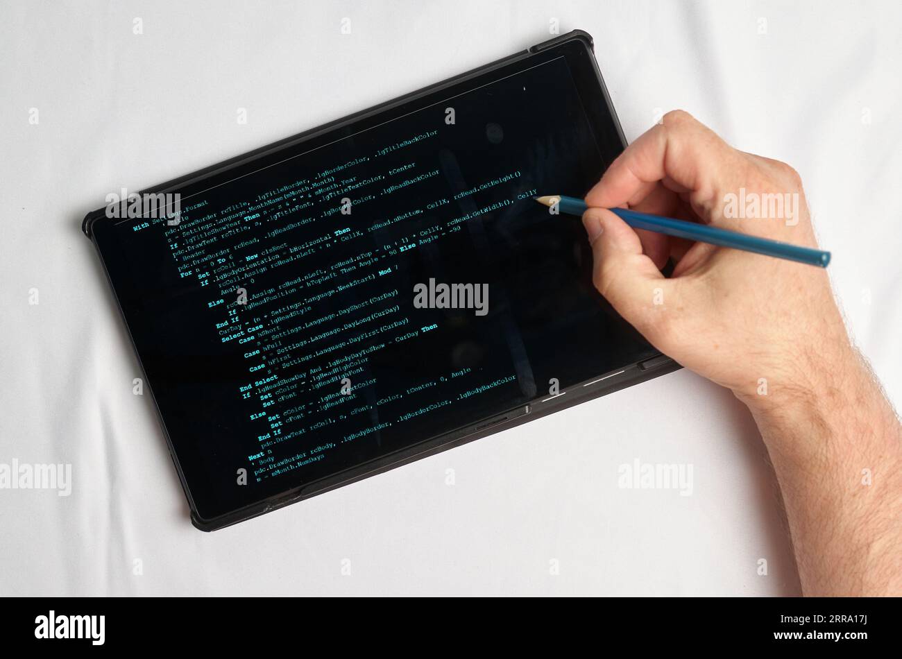 Programming and coding concept. A hand with a pencil writes a program listing on the screen Stock Photo
