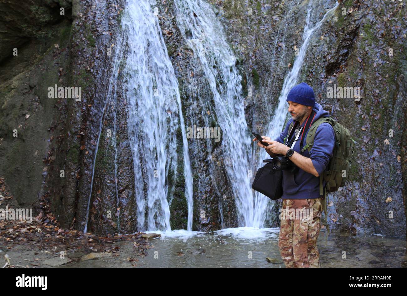 photographer standing near waterfall Stock Photo