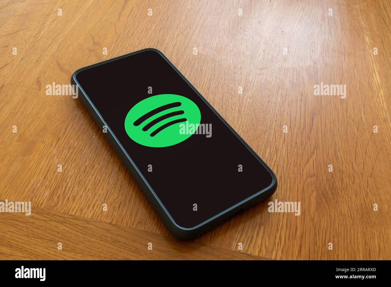 London, United Kingdom, 5th September 2023:- A mobile phone on a wooden table showing the Spotify streaming service’s logo Stock Photo