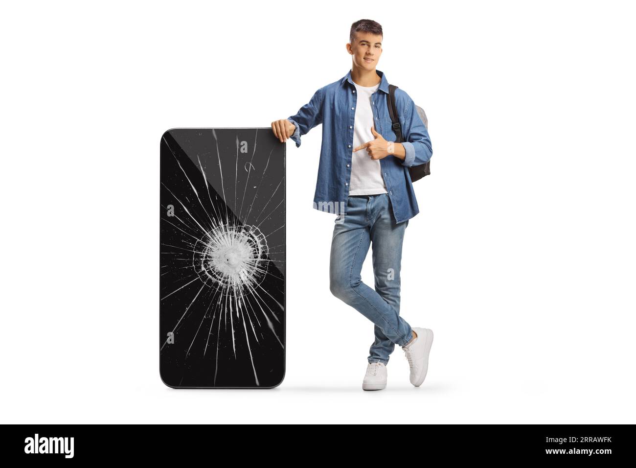 Male student with a backpack leaning on a big mobile phone and pointing at a broken screen isolated on white background Stock Photo