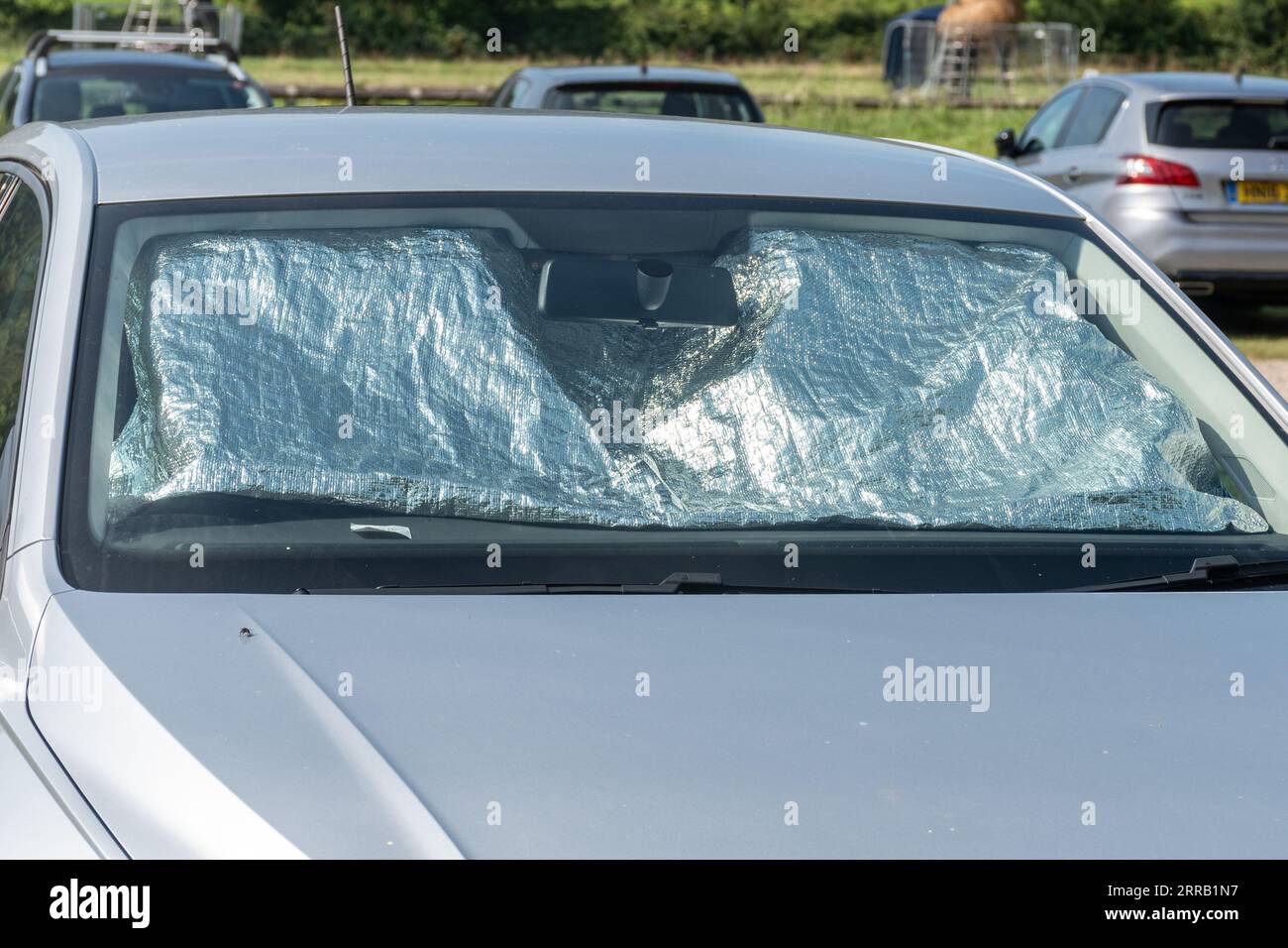 Car sun shade screen or sunshade covering the windscreen on a hot sunny day, UK Stock Photo