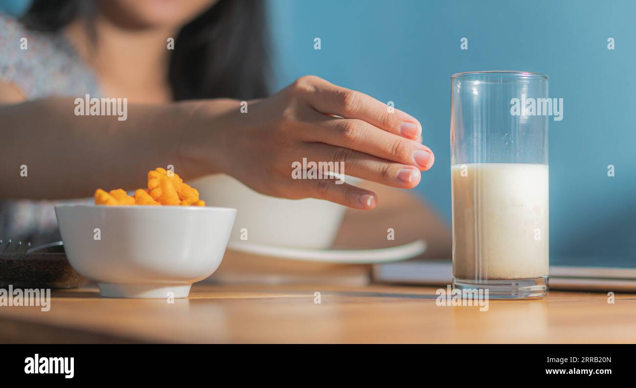 healthy woman eating corn flakes cereal while sitting and having