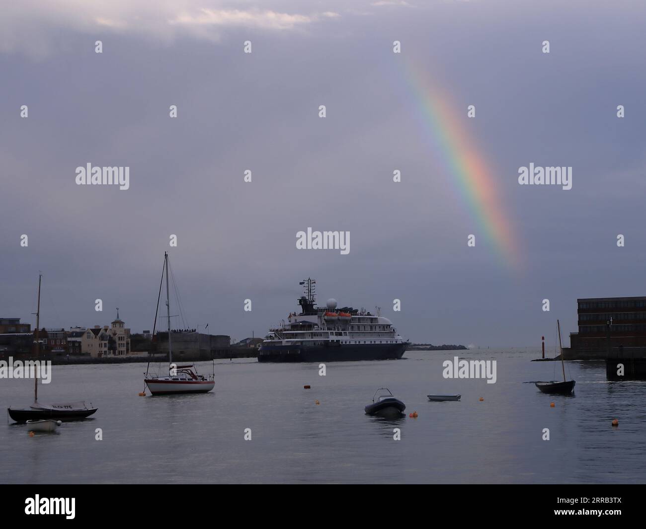 A cruise ship approaching the mouth of the harbour with a rainbow ...