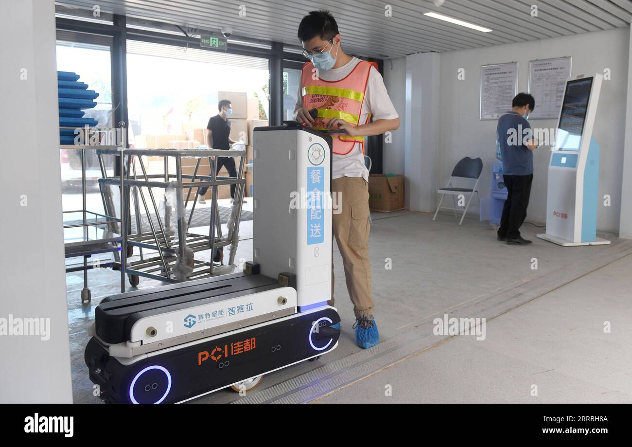 210923 -- GUANGZHOU, Sept. 23, 2021 -- A staff member regulates a meal delivery robot at the Guangzhou International Health Station in Baiyun District, Guangzhou City of south China s Guangdong Province, on Sept. 17, 2021. The first-phase project of the Guangzhou International Health Station will be put into operation soon, offering health service to inbound travellers during their quarantine period as required by epidemic prevention and control measures. The first batch of 184 medical workers moved in on Sept. 17 to make preparations for the health service for the travellers.  CHINA-GUANGZHOU Stock Photo
