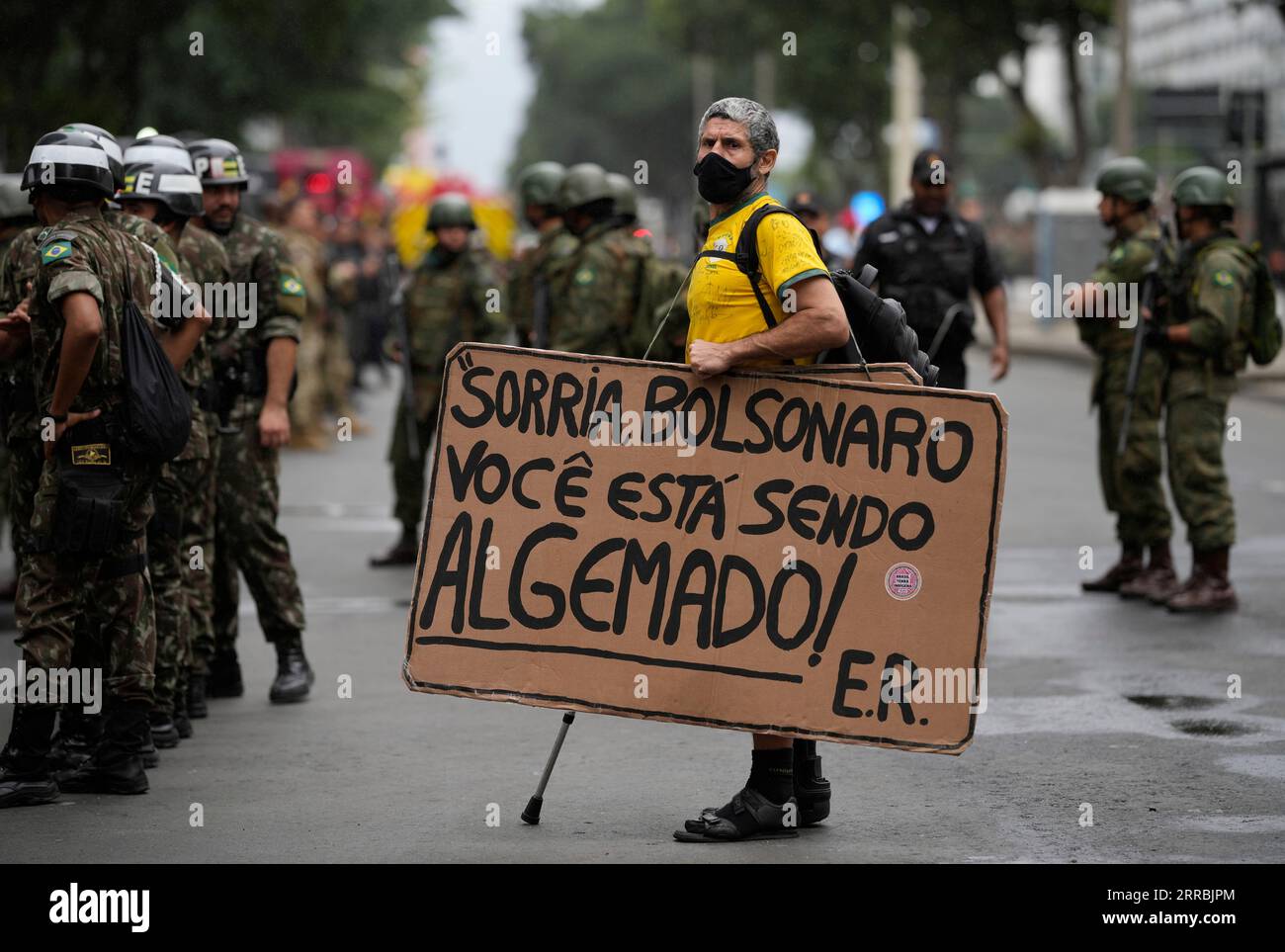 A protester holds a sign that reads in Portuguese "Smile Bolsonaro