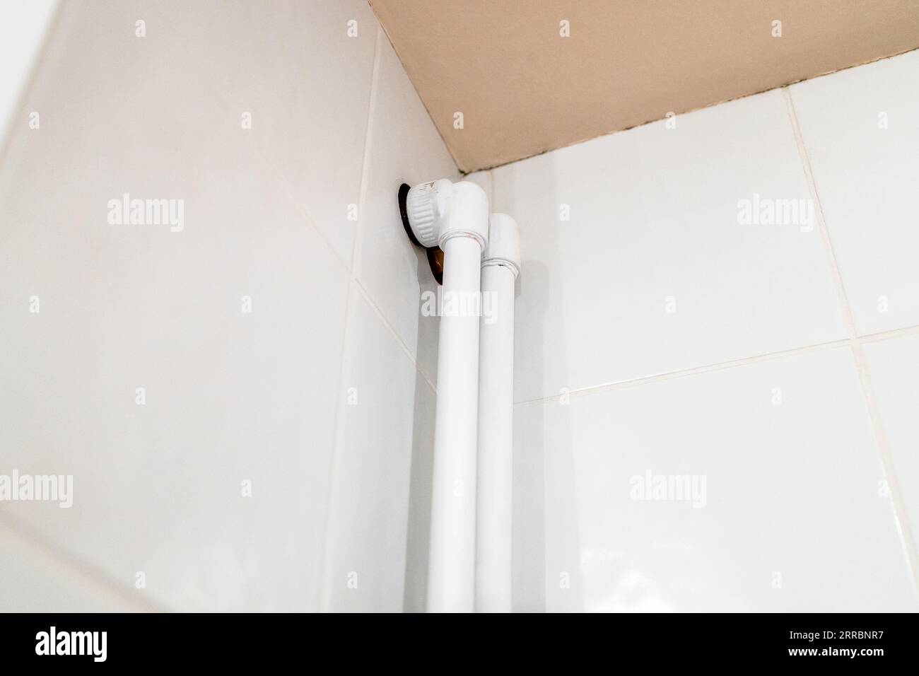 entry of polypropylene pipes at ceiling of bathroom on wall covered with ceramic tiles Stock Photo