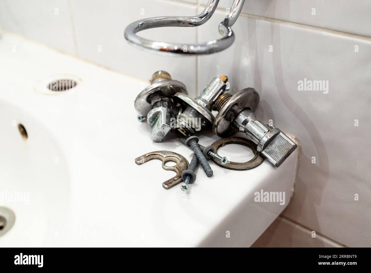 old ball valves and fixtures lie on edge of sink after removing the faucet Stock Photo