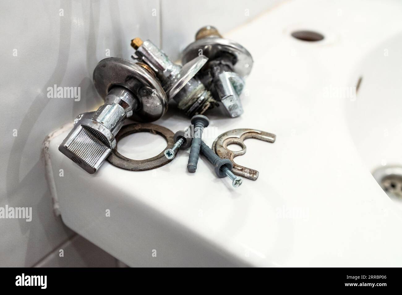 faulty ball valves and fixtures lie on edge of sink close up after removing the faucet Stock Photo