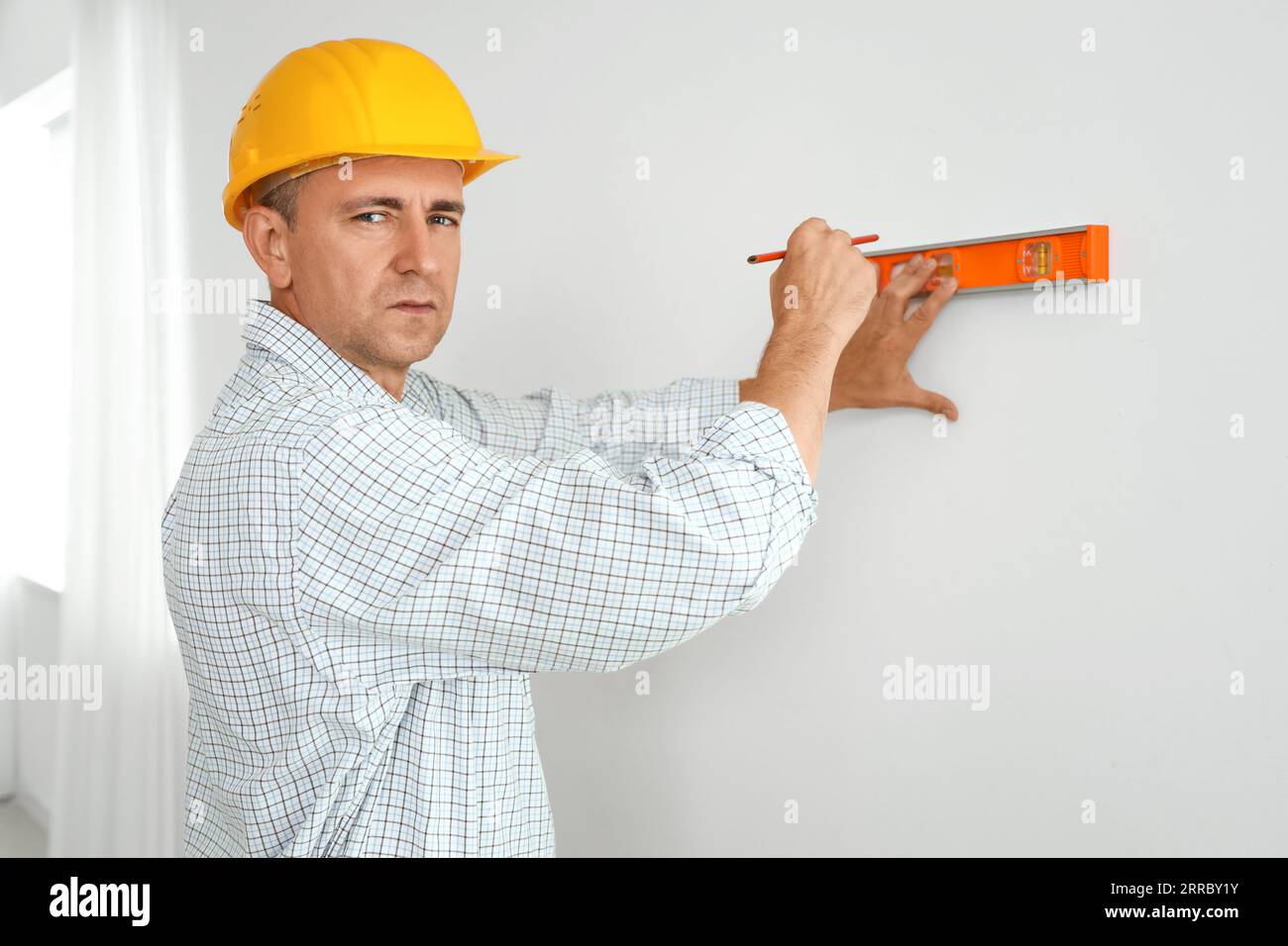 Builder Using Level Mature builder working with level in room Stock Photo - Alamy