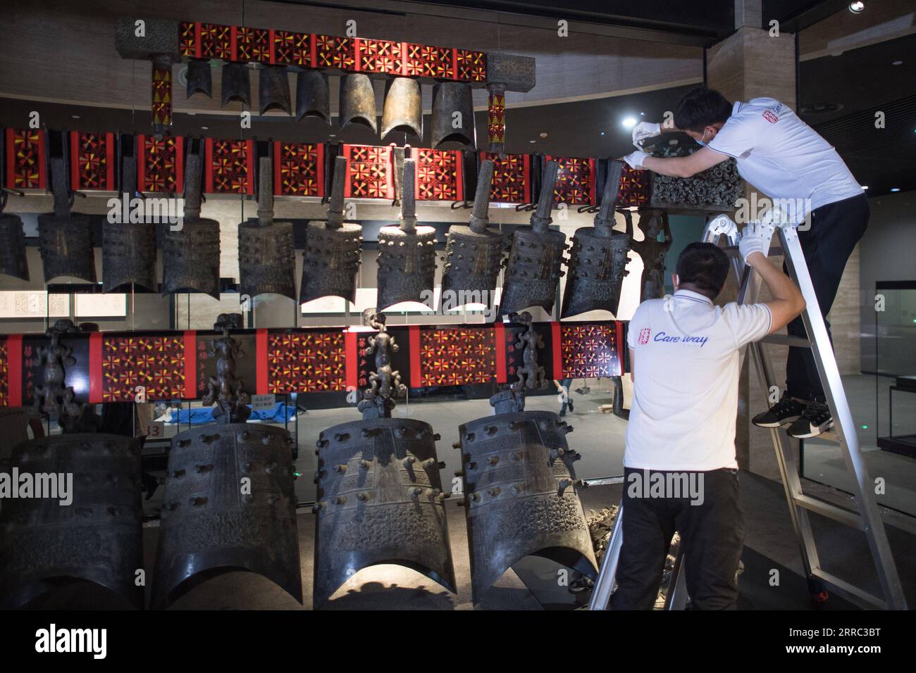 211015 -- WUHAN, Oct. 15, 2021 -- Staff members adjust chime bells after they were transferred to a newly-built exhibition hall of Hubei Provincial Museum in Wuhan, central China s Hubei Province, Oct. 15, 2021. The set of chime bells were recently relocated to the newly-built third phase project of the museum. Chime bell, or bian zhong in Chinese, is a percussion instrument that became prevalent in China from the Western Zhou Dynasty 1046-771 B.C.. The country s largest set of chime bells ever unearthed was found in 1978, also in Suizhou, in the tomb of Marquis Yi, a ruler of the ancient Zeng Stock Photo
