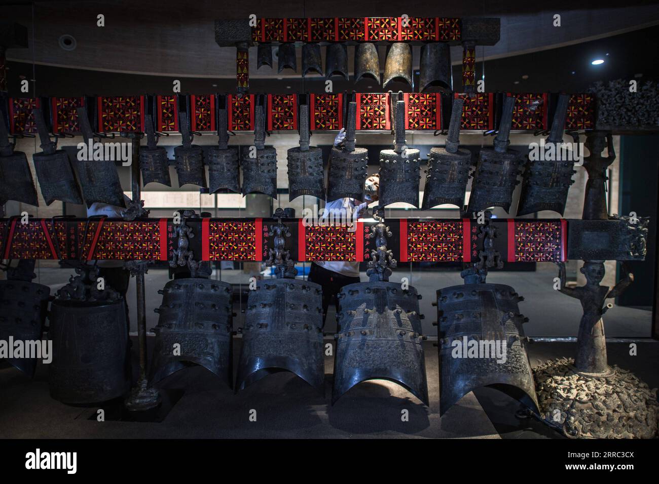 211015 -- WUHAN, Oct. 15, 2021 -- Staff members adjust chime bells after they were transferred to a newly-built exhibition hall of Hubei Provincial Museum in Wuhan, central China s Hubei Province, Oct. 15, 2021. The set of chime bells were recently relocated to the newly-built third phase project of the museum. Chime bell, or bian zhong in Chinese, is a percussion instrument that became prevalent in China from the Western Zhou Dynasty 1046-771 B.C.. The country s largest set of chime bells ever unearthed was found in 1978, also in Suizhou, in the tomb of Marquis Yi, a ruler of the ancient Zeng Stock Photo