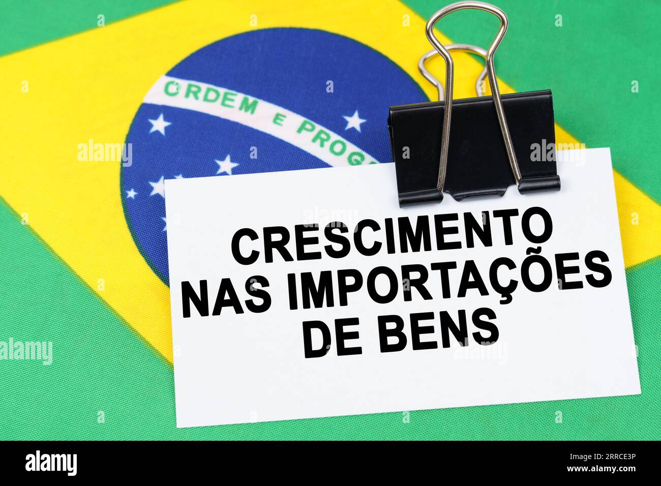 Economy and finance concept. On the flag of Brazil lies a business card with the inscription - growth in imports of goods. Text in Portuguese. Stock Photo
