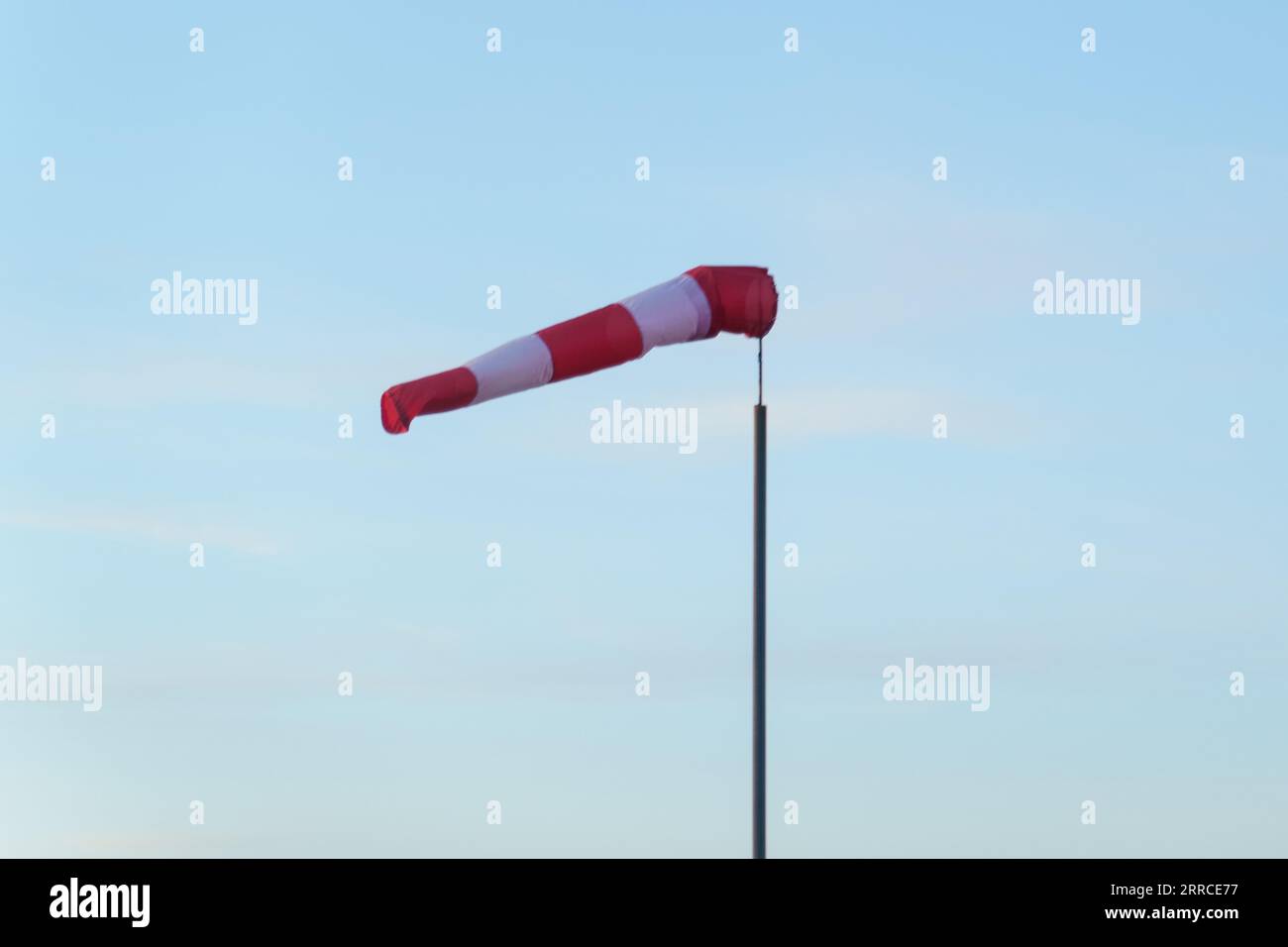 A red and white wind cone indicating the direction and strength of the wind. Strong wind, cone in horizontal position. Stock Photo