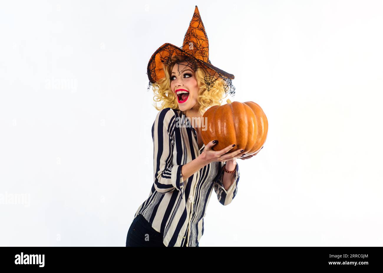 Happy girl in witch hat with pumpkin on Halloween party. Emotional woman in witch halloween costume with Jack-o-lantern. Preparation for Halloween Stock Photo