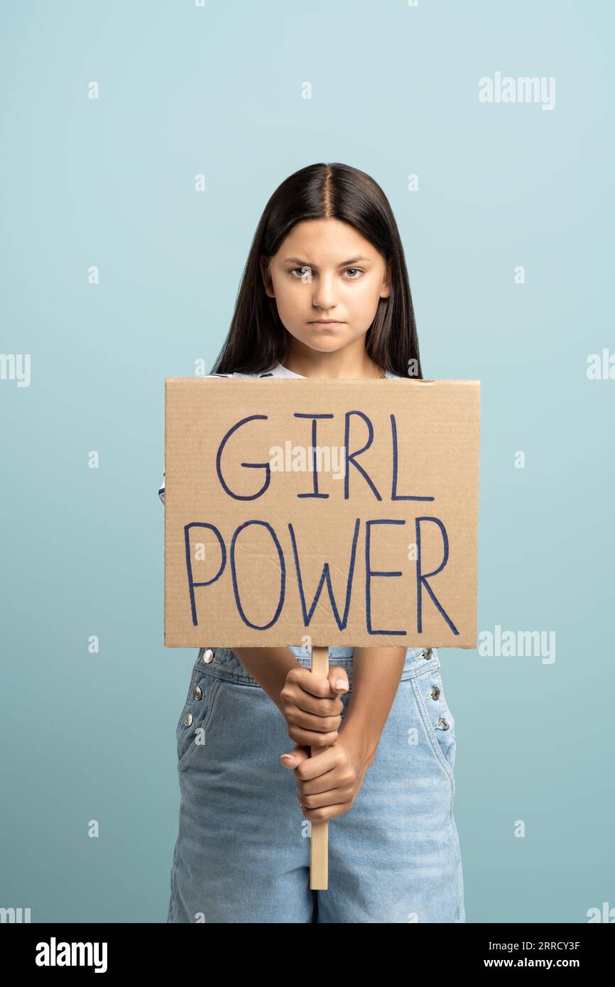 Serious confident teen girl showing holding girl power poster on blue ...