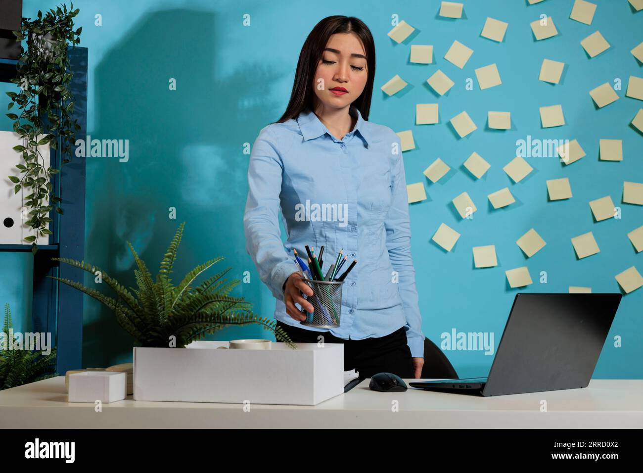 Sad female employee after being fired by boss picking up personal