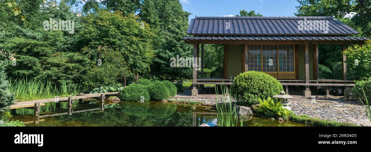 japanese garden with a pond, zigzag bridge, stone lantern and a tea house Stock Photo