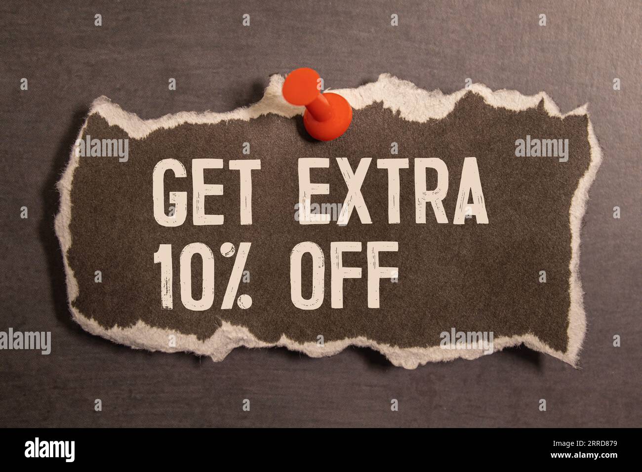 GET EXTRA 10 OFF percent text on a brown tag on a red paper background. Stock Photo