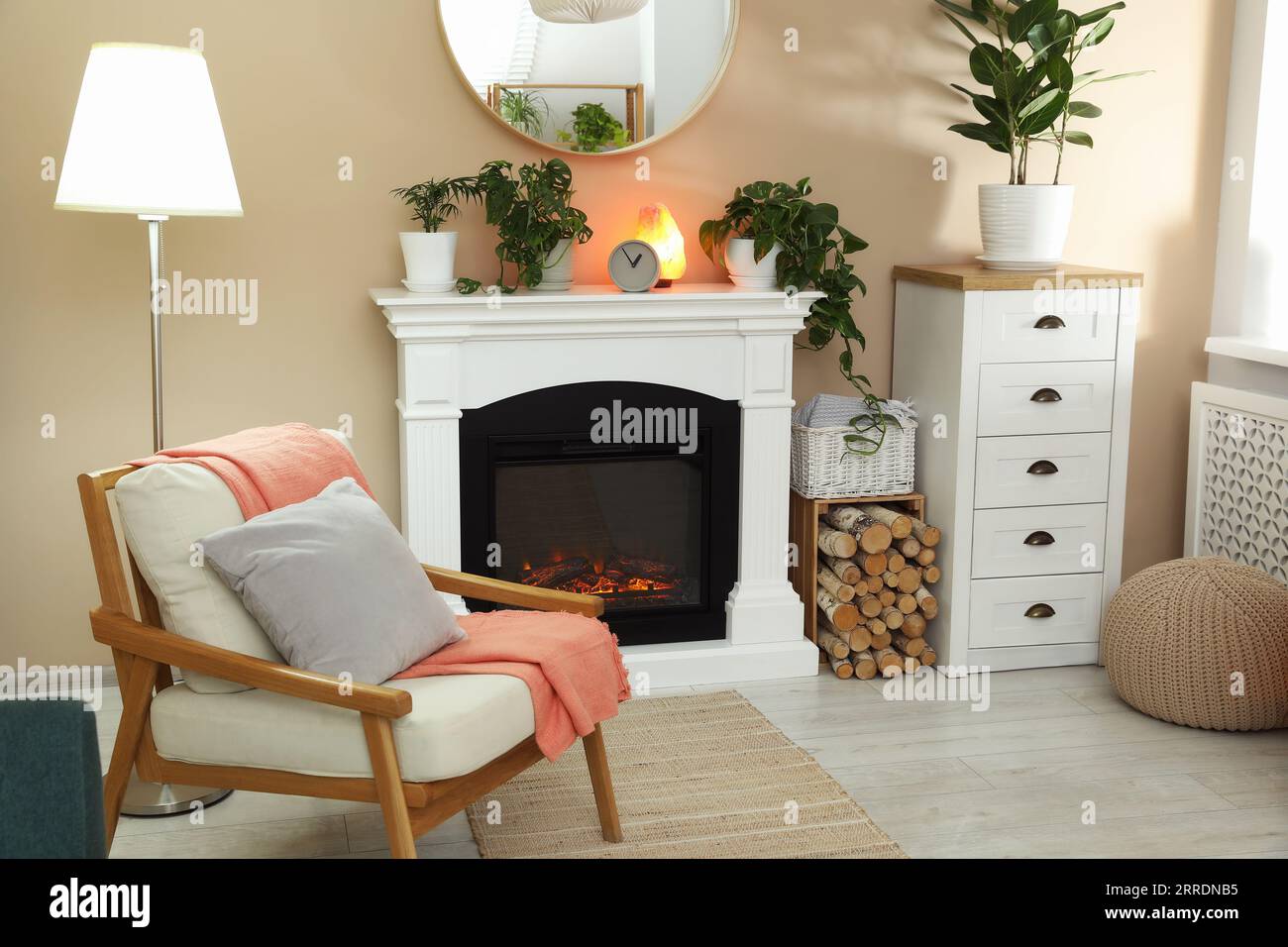 Stylish fireplace near comfortable armchair in cosy living room. Interior design Stock Photo