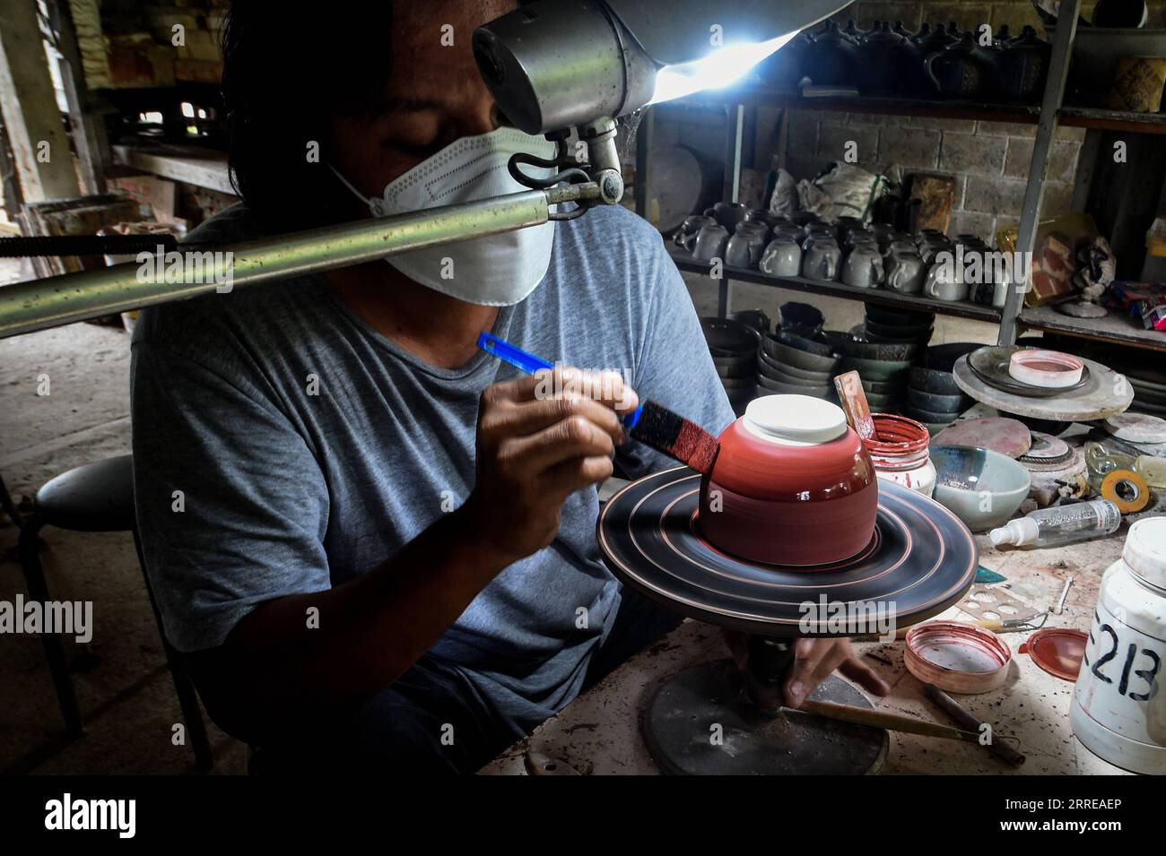 220214 -- WEST JAVA, Feb. 14, 2022 -- A craftsman paints a pottery at a workshop in Depok, West Java, Indonesia, Feb. 14, 2022.  INDONESIA-WEST JAVA-POTTERY MAKING AgungxKuncahyaxB. PUBLICATIONxNOTxINxCHN Stock Photo