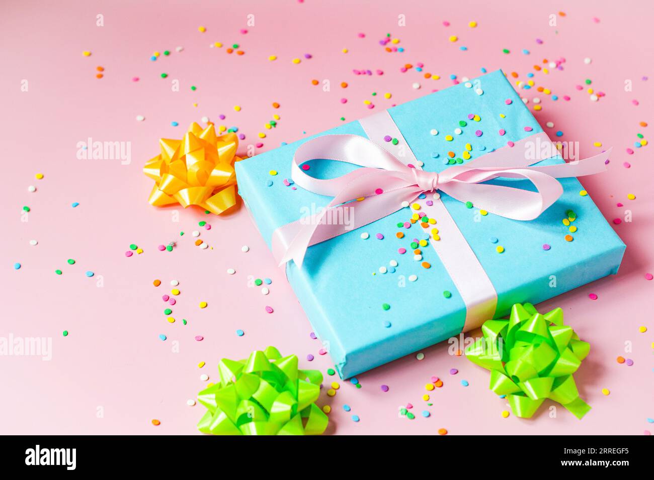 Gift wrapped in blue wrapping paper with pink, yellow and green bows Stock Photo
